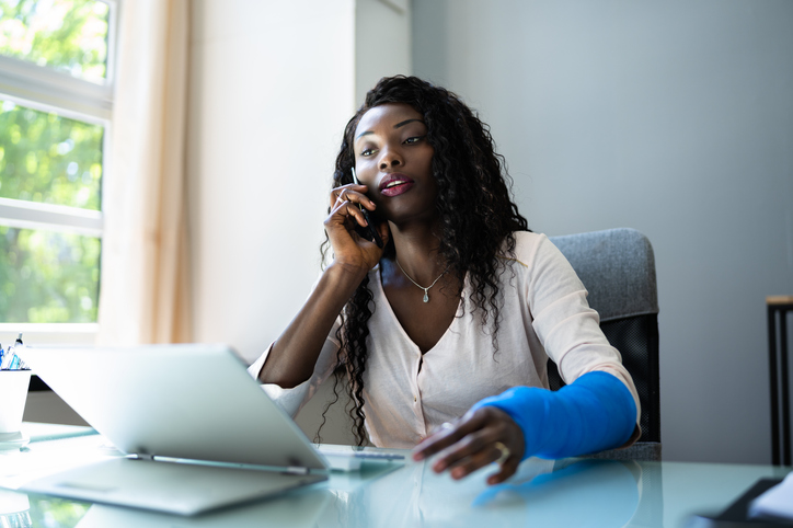 Woman with broken arm working with personal injury lawyer over the phone to manage appropriate compensation.